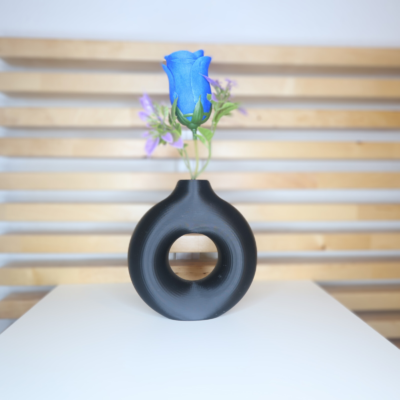 Jarrón Halo decorativo en color negro con diseño circular, colocado sobre una mesa con fondo de madera, ideal para aportar equilibrio y estilo a cualquier espacio