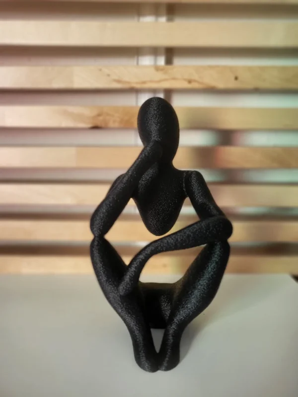 Figura Decorativa El Pensador en negro sobre fondo de madera